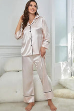 A soft blush pink satin contrast piping button-up top and pants pajama set with long sleeve length and black trim
