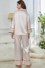 A soft blush pink satin contrast piping button-up top and pants pajama set with long sleeve length and black trim