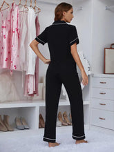 Black pajama set featuring contrast white piping with lapel collar and short sleeve length top and matching pants