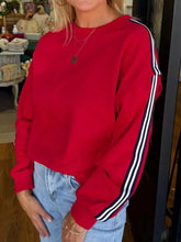 Red long-sleeved varsity sweatshirt with black and white striped sleeves made for machine wash cold care