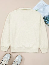 Cream-colored long-sleeved sweatshirt with soft texture, classic collar, ribbed cuffs, and zip collar patchwork design