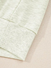 Light green heathered sweatshirt with ribbed cuffs featuring a striped patchwork zip collar design