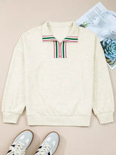 Cream-colored long-sleeved sweatshirt with a zip collar and green and pink striped patchwork zip trim