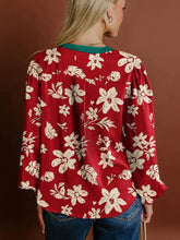 Red floral blouse featuring cream flowers and green trim with contrast tied neck shirred puff sleeves