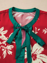 Red silk blouse with white floral print featuring contrast tied neck shirred puff sleeves and teal satin tie-neck detail