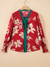 Red floral blouse with white blossoms and green accents featuring a contrast tied neck shirred puff sleeves and smocked cuffs