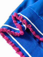 Bright blue knit short sleeve top with white stripes and vibrant pink pom trim ruffled detail