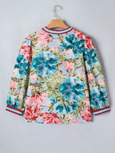 Floral blouse with vibrant blue and pink blossoms on light blue fabric featuring contrast red and white striped cuffs and v neck