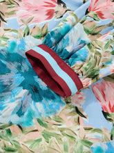 The floral blouse sleeve cuff features bold red and light blue stripes on soft gathered fabric with contrast trim