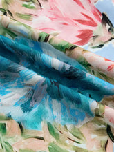 A lightweight floral blouse with a vibrant blue pink and green print featuring contrast trim v neck and cuffed bracelet sleeves