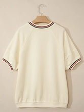 Cream-colored loose tunic top with contrast varsity striped neckline and cuffed short sleeve ribbed cuffs