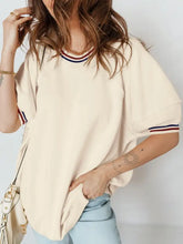 Cream-colored oversized tunic top with contrast varsity striped ribbed cuffs and neckline featuring red white and blue accents