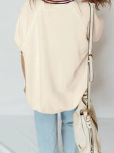 Cream-colored crossbody bag with white leather straps and gold-tone hardware paired with contrast varsity striped cuffed short sleeve tunic top