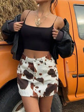 Cow print denim mini skirt featuring black and white cow print pattern in denim material for stylish casual wear