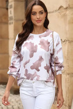 Woman in cow spots print puff sleeve sweatshirt and white pants