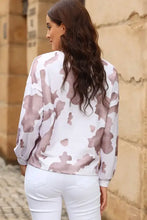Woman in cow spots print puff sleeve sweatshirt with white jeans