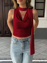 A sleek deep red cowl neck ruched sleeveless crop top with draped neckline and flowing side panel