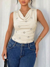 Cream-colored cowl neck sleeveless bodysuit with small black floral embroidery and a draped neckline