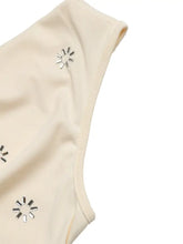 Cream-colored cowl neck sleeveless bodysuit with silver sunburst-shaped embellishments for elegant wear