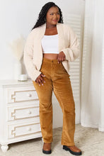 Cream boucle cropped cardigan with bell sleeve length over mustard high-waist corduroy pants