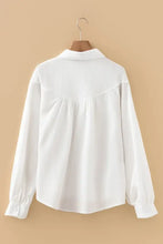 White long-sleeved blouse with crinkled texture and soft flowing silhouette featuring lantern sleeve button details