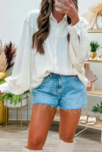 White long-sleeved button-up blouse with crinkled texture and lantern sleeve button details in relaxed fit
