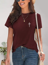 Woman in cross graphic round neck t-shirt, jeans, and straw hat