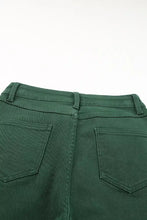 Dark green denim crossed waist raw hem shift jeans showing classic back pocket design on the back side