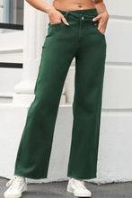 Dark green high-waisted denim jeans with crossed waist raw hem and straight-leg cut for a stylish casual look