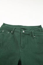 Dark green denim crossed waist raw hem shift jeans with silver-toned metal buttons and detailed stitching