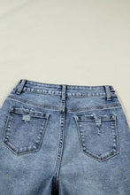 Back side of light-wash denim cuffed straight loose jeans with frayed distressed back pockets and high-rise waistband