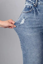 Medium-wash blue denim cuffed straight loose jeans featuring a distressed patch on the thigh