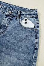 White iphone 13 with triple-lens camera in faded blue denim jeans pocket of cuffed straight loose jeans