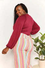 A woman wears a maroon culture code full size v neck neck bodysuit with puffed sleeves and high-waisted striped pants