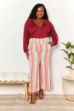 A woman wearing culture code full size v neck bodysuit paired with wide-leg pastel striped trousers