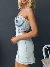 Light-wash denim cami dress with corset-style top and side cutouts in a cutout back sweetheart neck design