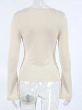 Beige long sleeve top with cutout knot front and flared cuffs in a fitted silhouette for stylish wear