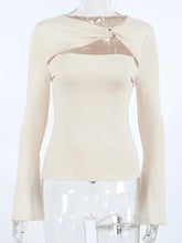 Beige long sleeve top with cutout knot front, twisted neckline, and sheer detail, ideal for stylish layering