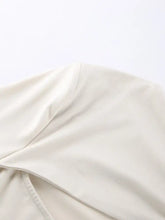 Cream-colored satin long sleeve top with cutout knot front and subtle stitching along the edge