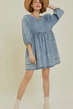A light-wash denim dress with a cutout round neck, puffed sleeves, and a tiered skirt