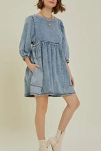 A light blue denim dress with cutout round neck, puffed balloon sleeves, and gathered waist detailing