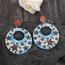 Pair of cutout star print wooden dangle earrings with blue and white celestial patterns