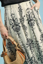 Beige and black floral umgee border print wide leg pants in lightweight flowing fabric with border print design