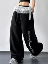 Black wide leg loose fit drawstring sweatpants with white lace trim at the waist and embroidered text on the leg
