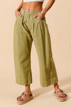Olive green wide leg mid rise chino pants with buttoned waistband pleats and care instructions label visible