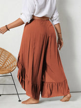 Plus size ruffled wide leg pants in rust color featuring flowing fabric and elastic waistband with ruffled hem