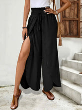 Black high-waisted side slit pants in polyester fabric with drawstring waist and machine wash care instructions