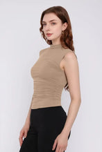 Beige sleeveless mock neck top with ruched details and black pants, machine wash cold