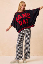 Black oversized top with bold red gameday lettering and trim paired with bibi gameday checkered printed pants