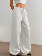 White loose-fitting wide leg drawstring casual pants with subtle vertical ribbing and adjustable waistband